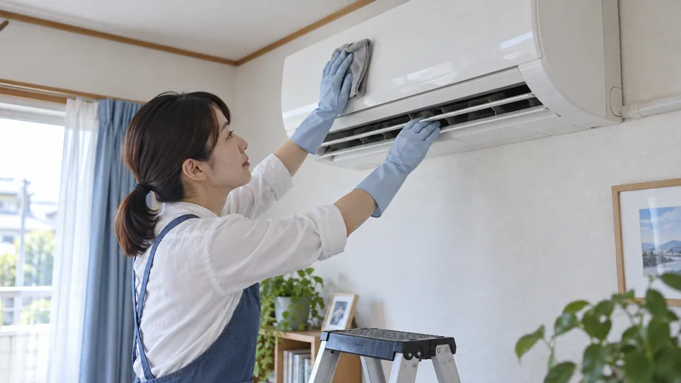電源を切った壁掛けエアコンの外装と吹出口表面を柔らかい布で拭く様子